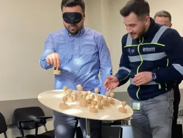 Gözü bağlı katılımcı ahşap figürleri yerleştirirken bir başka katılımcı yönlendiriyor.